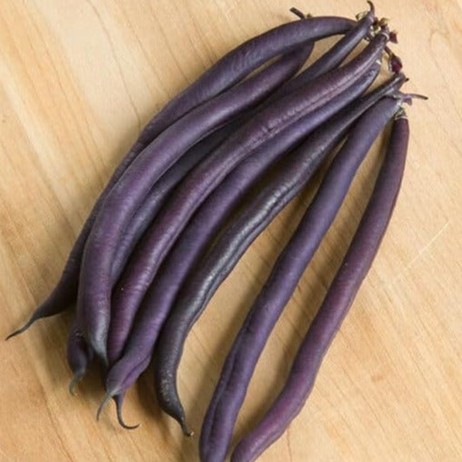 A group of Amethyst Purple beans on a wooden surface.
