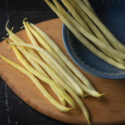 A photograph showing fresh yellow bush beans on a wooden surface, presumably the product mentioned in the description.
