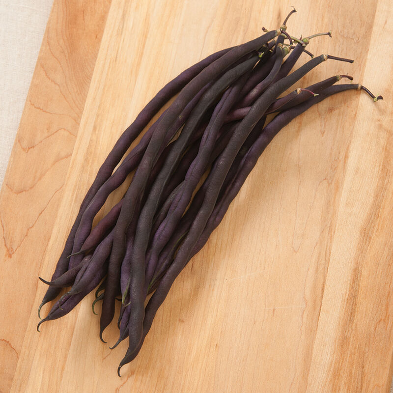 A bunch of purple pole beans on a wooden surface.