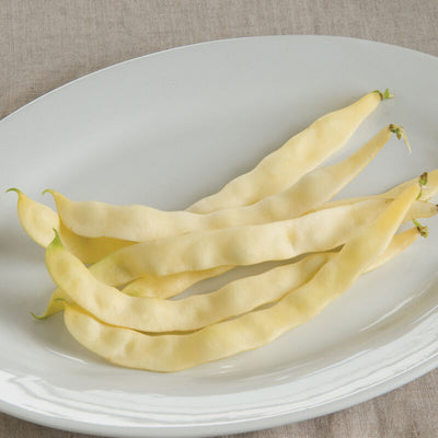 A white plate containing several fresh pole beans.