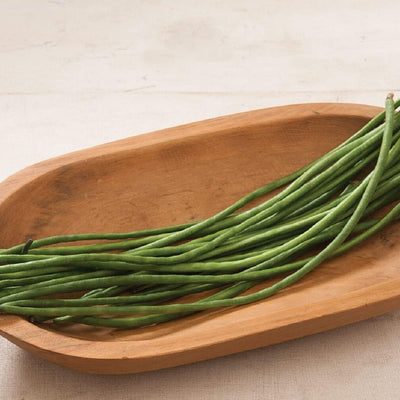 Green beans on a wooden plate with a neutral background