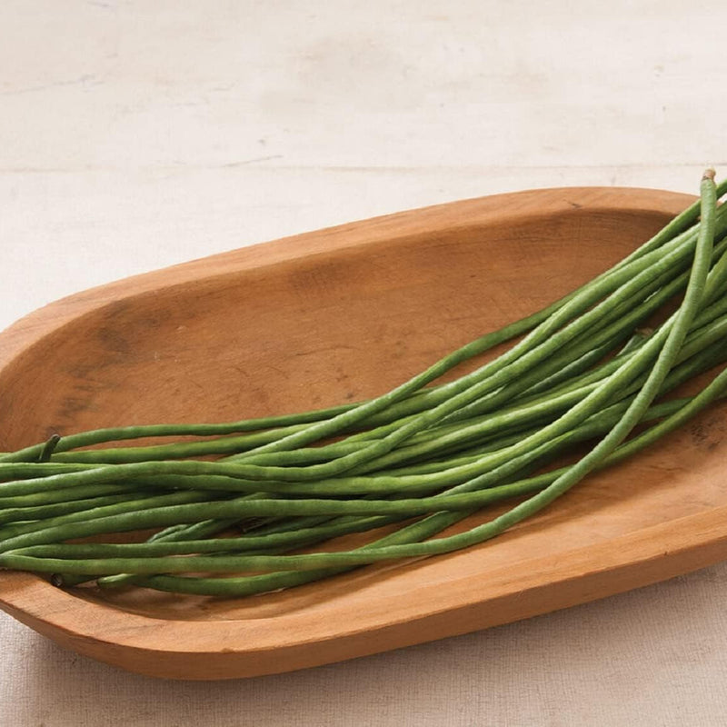 Green beans on a wooden plate with a neutral background