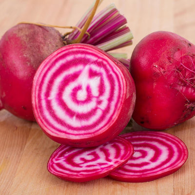 Image shows a group of red and white striped beet roots, with one whole root and a couple of sliced pieces revealing the vibrant colors and stripes.