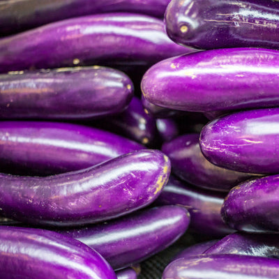 A close-up image of several long purple eggplants arranged together.