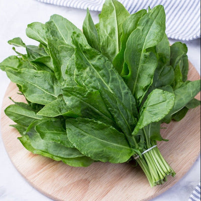 A bunch of fresh sorrel leaves on a wooden board, likely the product of the seeds sold by David's Garden Seeds.