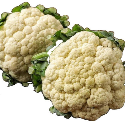 Two fresh heads of cauliflower with green leaves attached, placed on a wooden cutting board with a knife beside them, on a wooden surface.