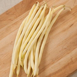 A bundle of white, stringless beans laid out on a wooden surface, representing the Monte Gusto pole bean variety.