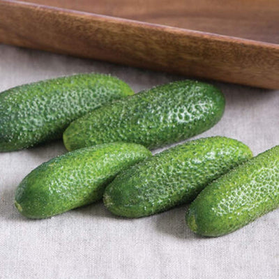 A group of fresh cucumbers on a linen surface.
