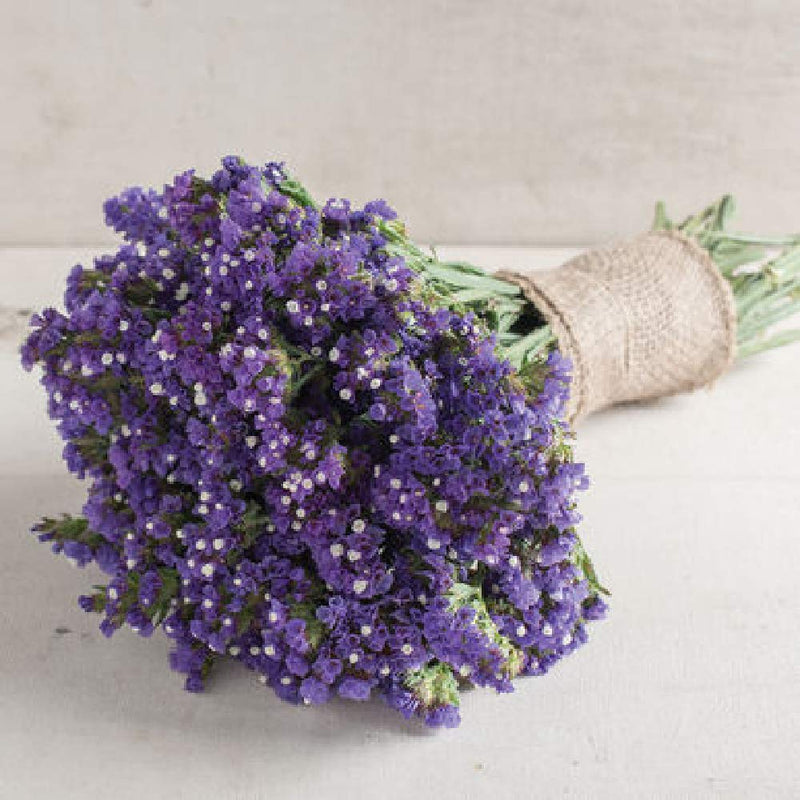 A bundle of dried blue statice flowers wrapped with a burlap ribbon, likely used for crafting or decorative purposes.