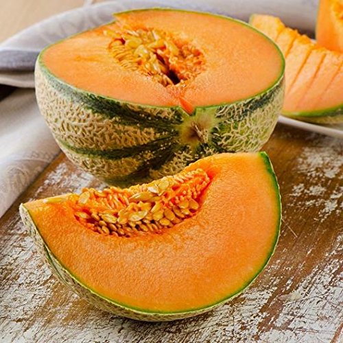 A partially sliced Charentais melon displaying the orange flesh and green, textured outer surface, placed on a wooden surface with a blurred background.
