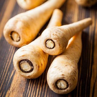 A group of fresh parsnips with visible hollow centers, placed on a wooden surface.