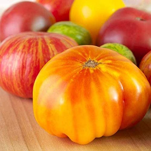 A cluster of Beefsteak tomatoes with red and yellow streaks on a wooden surface.